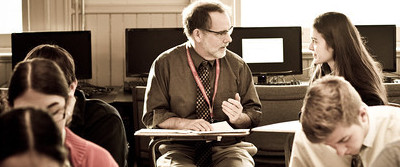 Upper school teacher, Randy Gehman, helps student in class.