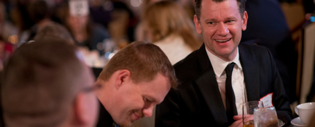 Men sitting around a table at a Remember America Speakers Series dinner