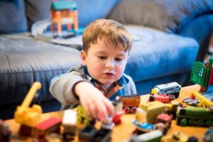 A child plays with wooden toy trains.