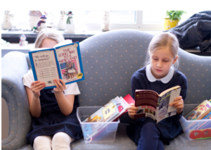 Two Dayspring elementary students read on a couch during class.