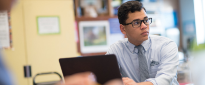 A student at Dayspring Christian Academy in Lancaster PA looks up from behind his laptop in the classroom.