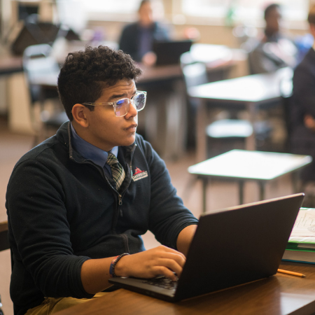 A high school student taking notes on a laptop at Dayspring Christian Academy.