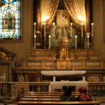 Two people sitting at a pew and praying in a church in Rome.